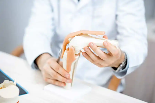 Reha nach TEP - Arzt mit Modell eines Knie-Gelenks