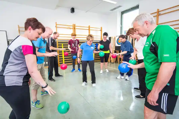 Reha-Nachsorge: Sportgruppe dribbelt Bälle mit der Hand Reha-Nachsorge: Sportgruppe dribbelt Bälle mit der Hand