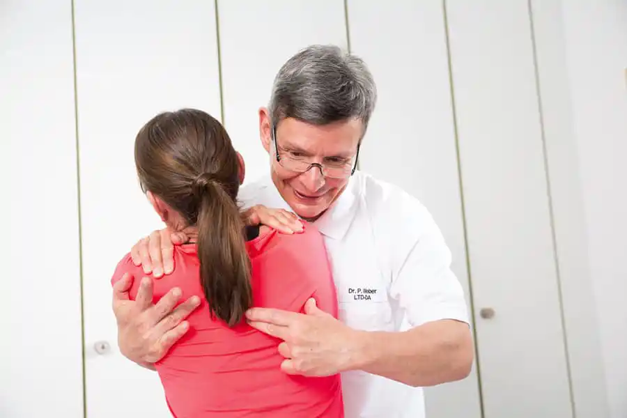 Reha-Behandlung: Patientin wird von Arzt am Rücken behandelt