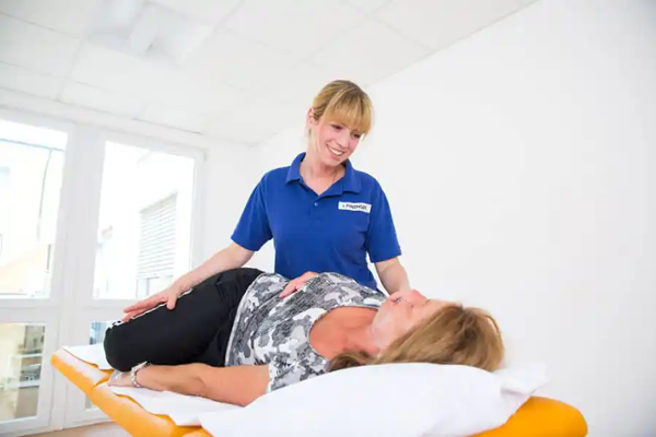 Physiotherapie bei Reha: Therapeutin behandelt Patientin auf Liege Physiotherapie bei Reha: Therapeutin behandelt Patientin auf Liege